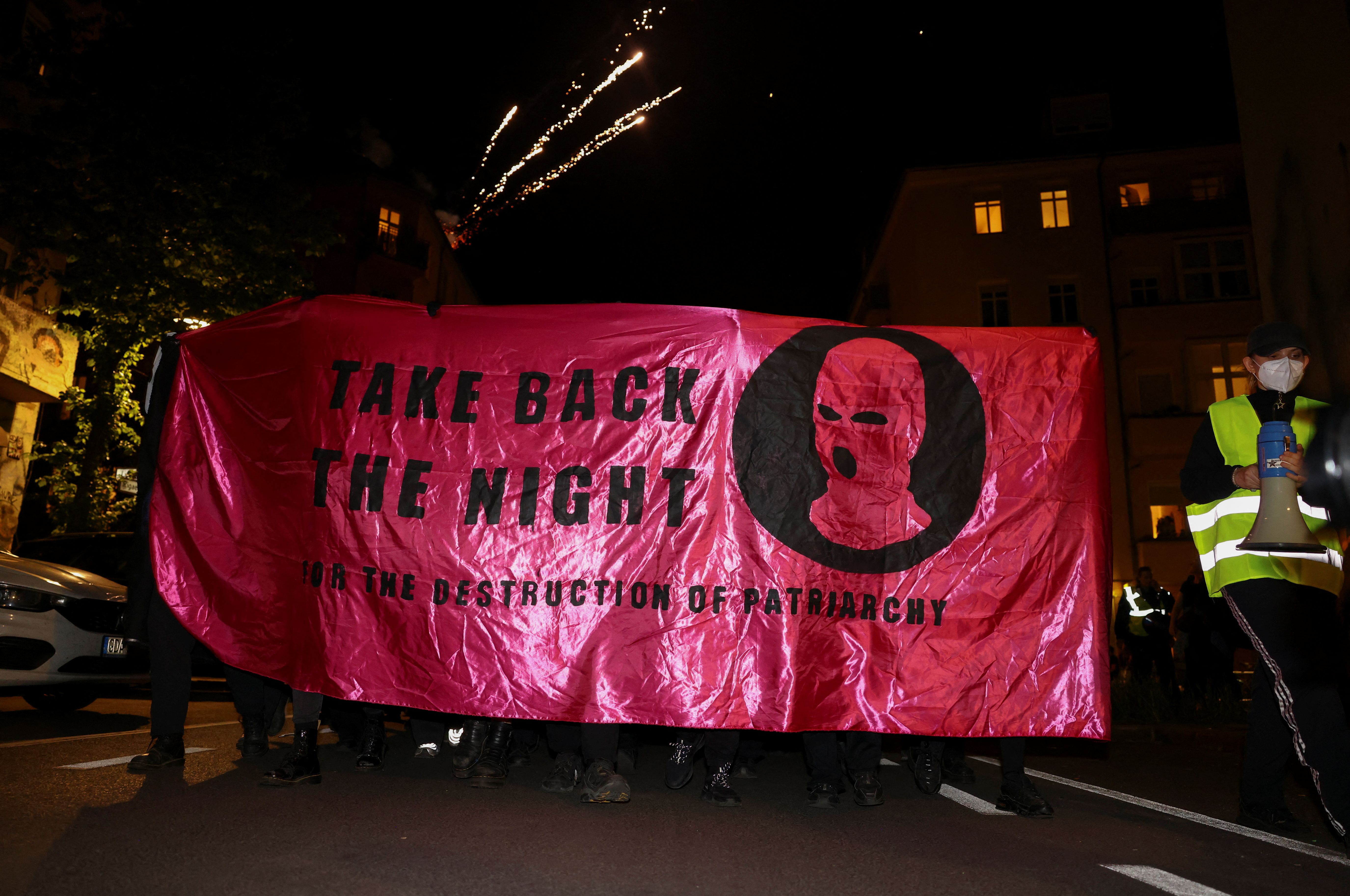 Mitglieder der Black Bloc-Gruppe hielten ein riesiges Banner mit der Aufschrift „Nimm die Nacht zurück für die Zerstörung des Patriarchats“ hoch, mit einer maskierten Person als Symbol