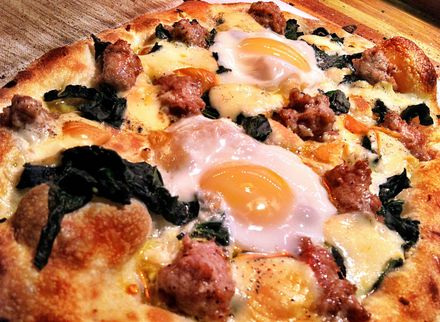 a pizza pie with eggs and sausage.