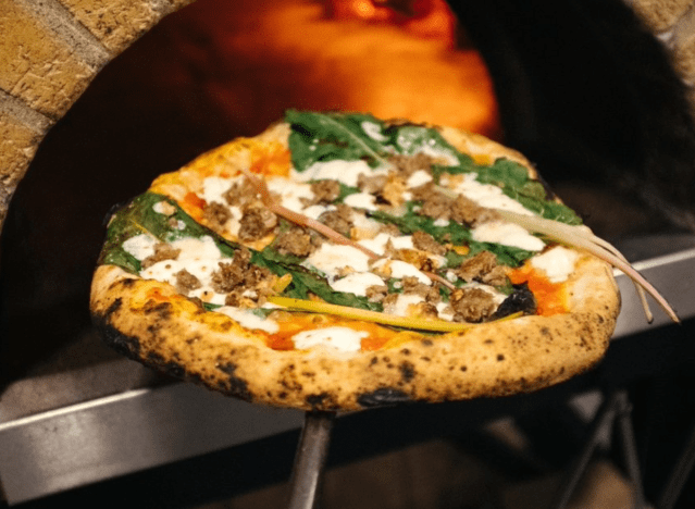 a wood fired pizza coming out of a pizza oven.