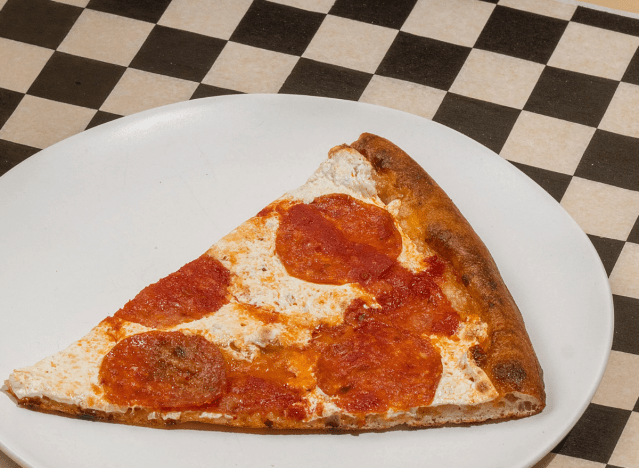 a slice of pepperoni pizza on a checkered background.