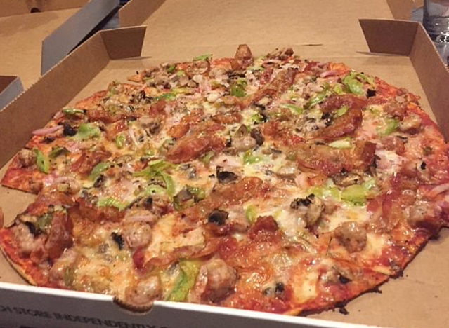 a pizza in a pizza box loaded with toppings.