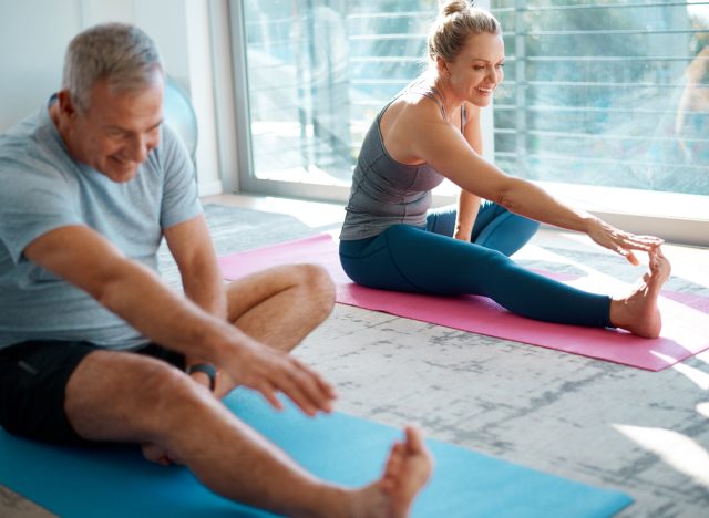Älteres Paar, das sich zu Hause auf Yogamatten dehnt