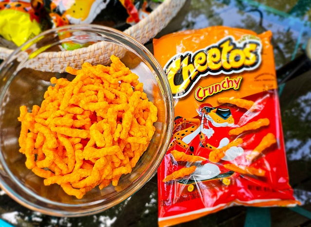 eine Schüssel mit knusprigen Cheetos neben einer Tüte.