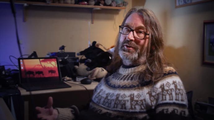 Jeff Minter trägt einen Pullover und spricht in die Kamera in Llamasoft: The Jeff Minter Story.